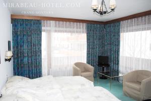 - une chambre avec un lit, deux chaises et une télévision dans l'établissement Hotel Mirabeau, à Crans-Montana