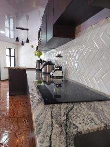 a kitchen with a black counter top and white tiles at Villa Dreams Irazu in Cartago