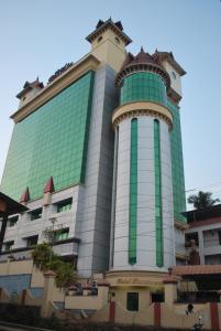 a tall building with a green and white at hotel bessota international in Thiruvalla