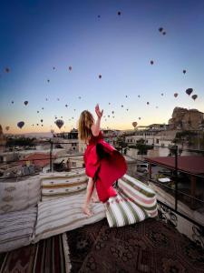 ギョレメにあるAdora Cave Suites -の熱気球付きの建物の上に飛び乗る女