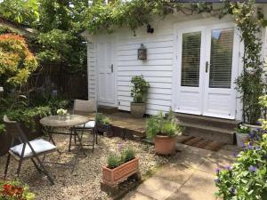 um pátio com uma mesa, cadeiras e plantas em Garden Studio em Cranbrook