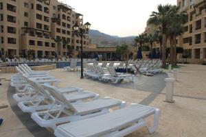 een rij witte ligstoelen op een binnenplaats bij Samarah Dead Sea Resort Studio-CP6 Traveler Award 2023 Winner in Sowayma