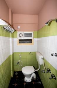 a bathroom with a toilet and green and pink at Navanidhi Comforts in Bangalore