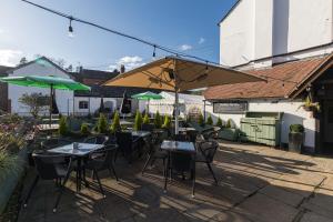 un patio con mesas, sillas y una sombrilla en The Littleton Arms en Penkridge