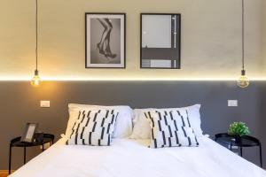 a bedroom with a white bed with three pictures on the wall at Amazing studio in the city center + WiFi in Trieste