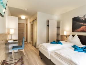 a hotel room with two beds and a blue chair at Hotel Sportwelt in Zauchensee