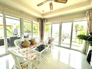 a living room with a couch and chairs and windows at RIM Chaam By RoomQuest in Cha Am
