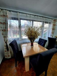 a dining room table with chairs and a vase of flowers on it at Casa Adelina in Băile Herculane