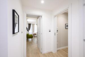 a hallway with white walls and a room with a green chair at Alma Suites in Naples