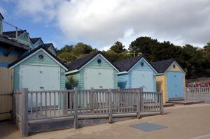 a row of beach huts behind a wooden fence at The Riviera Hotel & Apartments - Alum Chine in Bournemouth