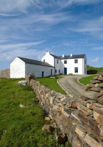 a white house behind a stone wall at Termon House in Dungloe