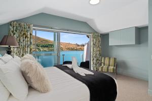 a bedroom with a large bed with a large window at Lake Front 3-bedroom Apartment with Lake Access in Queenstown
