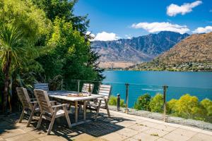 a table and chairs on a patio with a view of a lake at Lake Front 3-bedroom Apartment with Lake Access in Queenstown