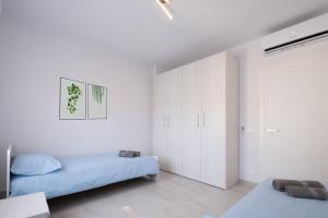 een witte slaapkamer met 2 bedden en een kast bij casa la riviera sanremo in Sanremo