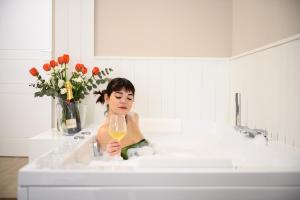 Eine Frau, die in einer Badewanne sitzt und ein Weinglas hält. in der Unterkunft Alma Suites in Neapel
