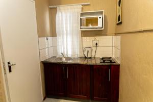 a small kitchen with a sink and a microwave at The Hide in Randburg in Johannesburg +121 photos