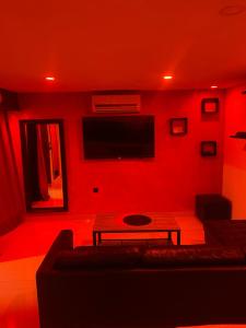 ein rotes Wohnzimmer mit einem Sofa und einem TV in der Unterkunft love love 23 in Villeurbanne