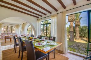 a dining room with a table and chairs and a large window at Can Comaro in Alcudia