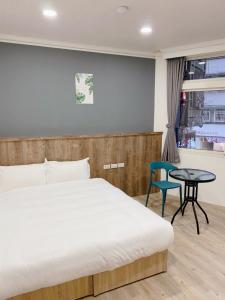 een slaapkamer met een bed, een tafel en een raam bij Benz 賓士溫泉旅館 in Jiaoxi