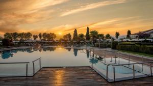 a swimming pool with a sunset in the background at Hotel Caesius Thermae & Spa Resort in Bardolino