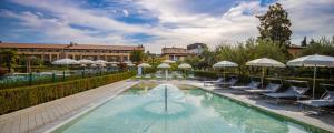 a swimming pool with chairs and umbrellas next to a building at Hotel Caesius Thermae & Spa Resort in Bardolino