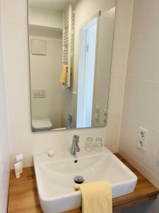 a white bathroom with a sink and a mirror at Creo München Süd in Munich