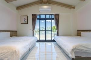 two beds in a room with a large window at Dragon Crane Resort in Puli