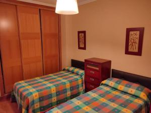 a bedroom with two beds and a dresser and a cabinet at Precioso piso al lado de las playas en Portonovo in Sanxenxo