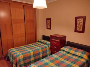 a bedroom with two beds and a dresser and a cabinet at Piso espectacular al lado de las playas en Portonovo in Sanxenxo