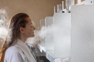 a woman standing in front of a wall with steam coming at Hotel Caesius Thermae & Spa Resort in Bardolino