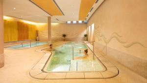 two people in a swimming pool in a hotel at Hotel Caesius Thermae & Spa Resort in Bardolino