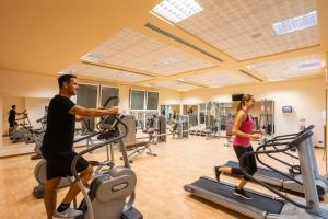 a man and woman exercising on treadmills in a gym at Hotel Caesius Thermae & Spa Resort in Bardolino