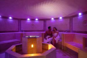 a man and woman sitting in a room with purple lights at Hotel Caesius Thermae & Spa Resort in Bardolino