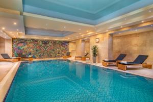 a swimming pool in a hotel with chairs and a painting at Hotel National in Yerevan