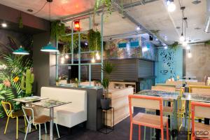 a restaurant with tables and chairs and plants at Ekho Hotel Grenoble Nord Saint Egrève in Saint-Égrève