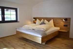 a bedroom with a bed with a wooden headboard at Ferienwohnungen Kirchenwirt in Thiersee