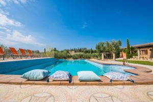a swimming pool with pillows sitting on a wooden bench at Ideal Property Mallorca - Ses Comes in Selva +43 photos