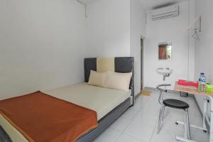 1 dormitorio con cama, escritorio y silla en Shekinah Homestay & Cafe Waikabubak Mitra RedDoorz, en Waikabubak