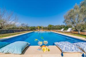 a swimming pool with two wine glasses and a table at Ses Planes in Búger