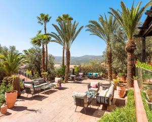 eine Terrasse mit Palmen, Stühlen und Tischen in der Unterkunft Widiane Resort in Bine el Ouidane