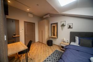 Un dormitorio con una cama, un escritorio y una mesa. en Manoir Apartments City Center, en Novi Sad