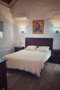 a bedroom with a large bed with white sheets at Hacienda Sajorami in Zahora
