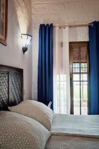 a bedroom with a bed with blue curtains and a window at Hacienda Sajorami in Zahora