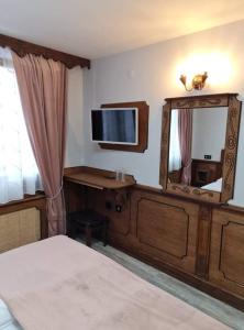 a bedroom with a mirror and a tv on the wall at Chuchura Family Hotel in Koprivshtitsa