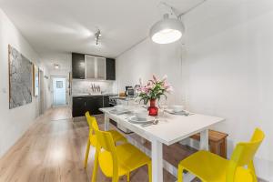 a kitchen with a white table and yellow chairs at Holiday 33 Apartments ABCD Alexanderplatz in Berlin