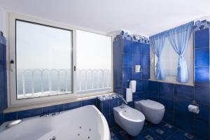 La salle de bains est pourvue de carrelage bleu, d'une baignoire et de toilettes. dans l'établissement Hotel La Ninfa, à Amalfi