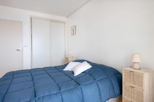 a blue bed in a white bedroom with a night stand at Magnifique vue mer pour un sejour Baulois in La Baule