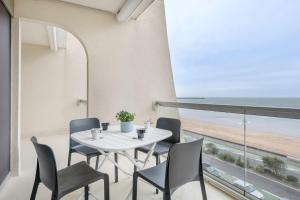 a dining room with a table and chairs and the beach at Magnifique vue mer pour un sejour Baulois in La Baule