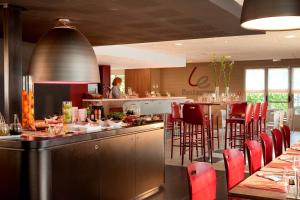 un restaurante con un bar con mesas y sillas rojas en Campanile Valenciennes - Petite-Forêt, en Petite Forêt