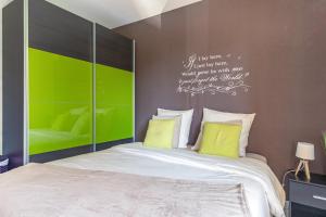 1 dormitorio con 1 cama con almohadas verdes y blancas en L'anisé, en Metz